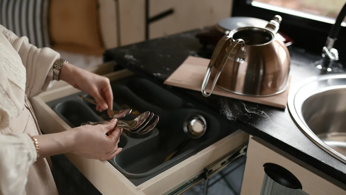 Kitchen drawer with utensil organizer beside a sink
